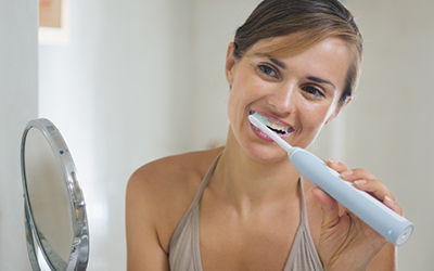 Woman brushing her teeth with an electric toothbrush