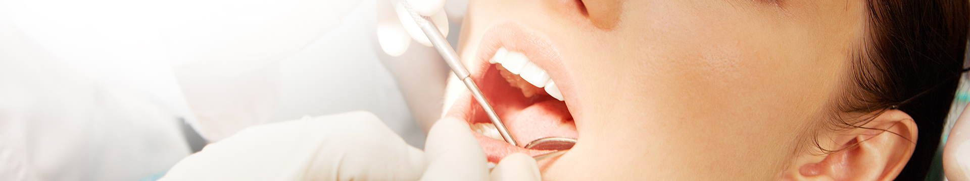Close-up of womans mouth being examined in dental chair
