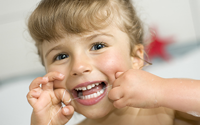 A young girl flossing teeth