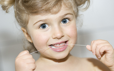 Young girl flossing her teeth